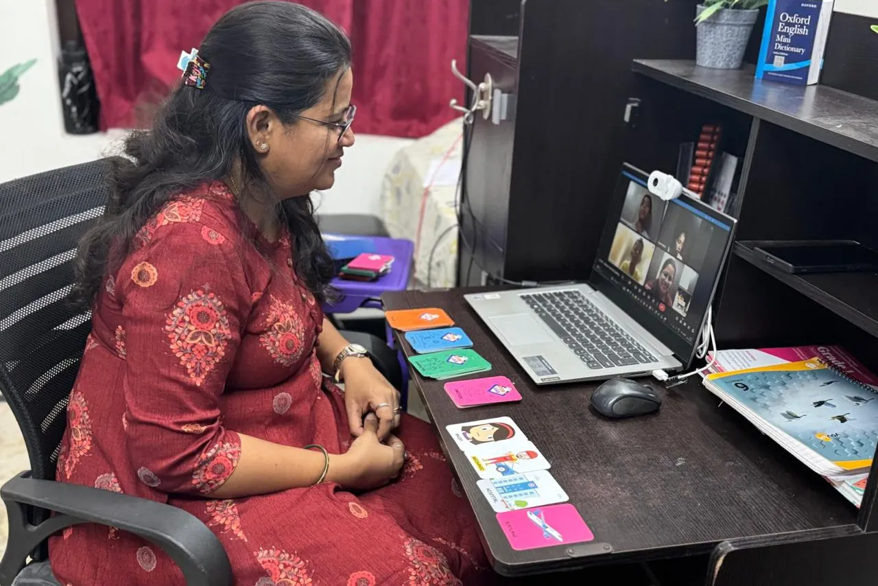 Shruti teaching a live online class from her desk, with learning cards in front of her