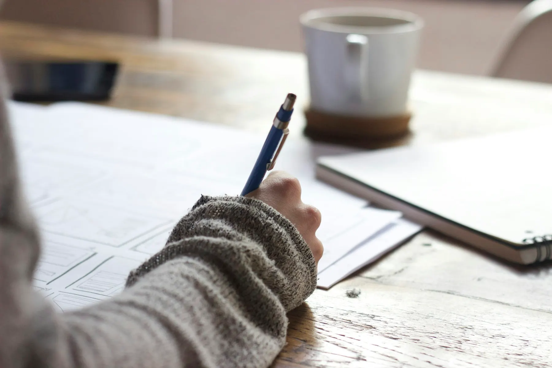 A learner writing in a notebook beside study materials